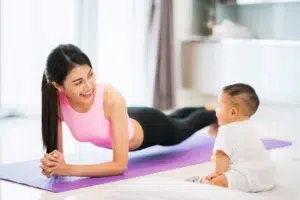 A mother exercising while watching her baby.